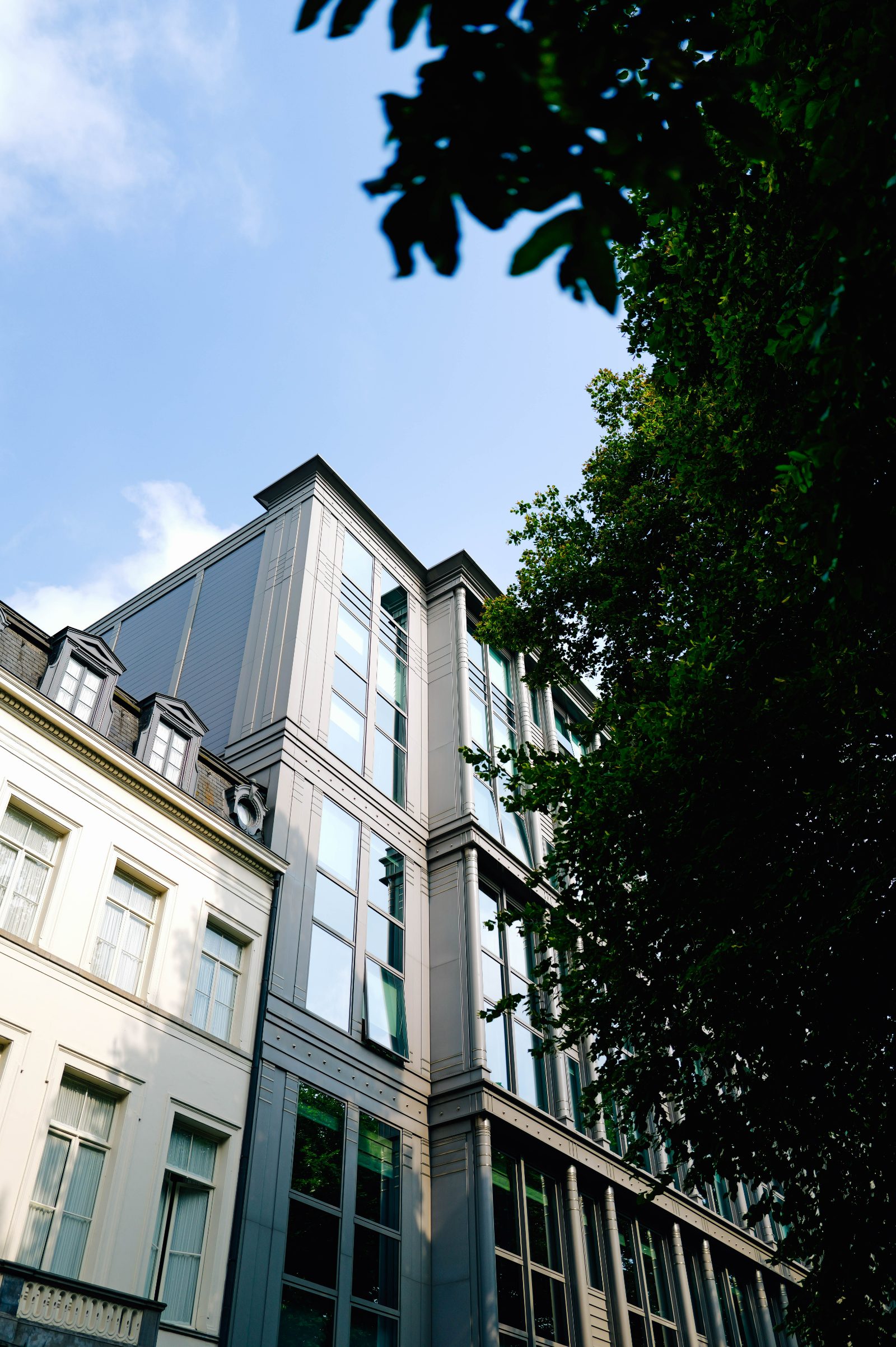 Moderne Glas- und Metallfassade eines Wohn- und Geschäftsgebäudes neben einem Altbau